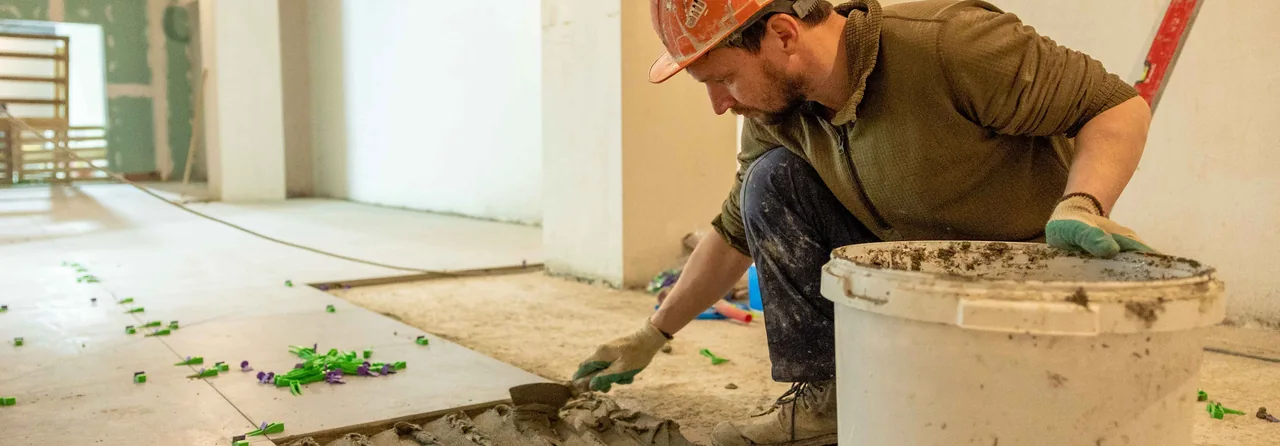 Construction worker laying flooring. Illustrative stock photograph, not a Backbone customer.